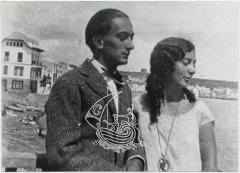 Black and white photograph of Anna Maria and Salvador Dalí on a cove, with some boats behind them.