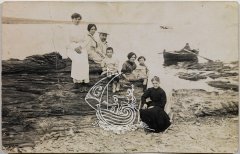 Fotografía antigua en blanco y negro. La familia Dalí en una cala, con una barca de pesca detrás.