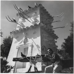 Fotografia de Salvador Dalí sota la torre de la Casa Museu de Portlligat. La fotografia és en blanc i negre.