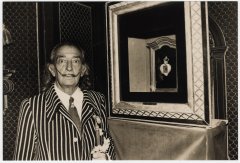 Fotografía en blanco i negro de Salvador Dalí junto a una de sus obras que forma parte de la colección de joyas del artista